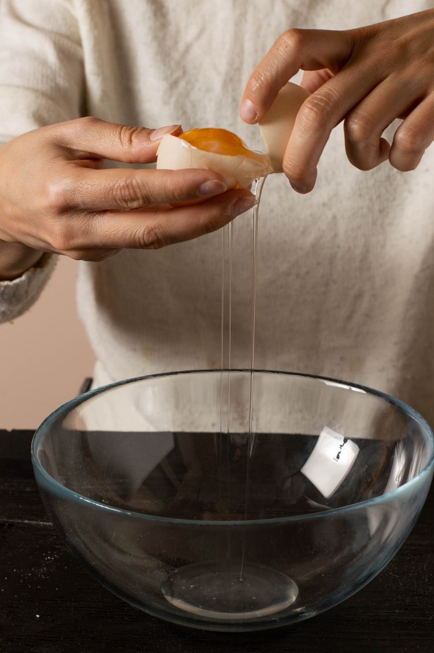 a person putting egg on the bowl